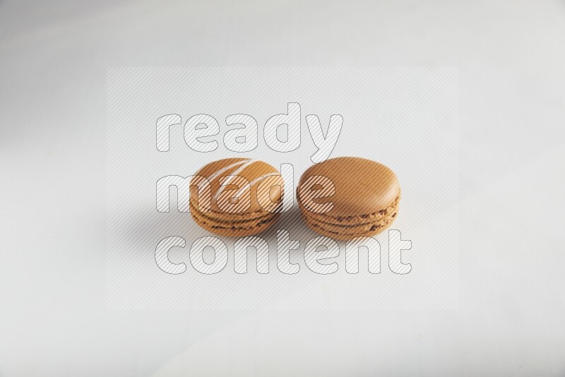 45º Shot of of two assorted Brown Irish Cream, and Brown Maple Taffy macarons  on white background