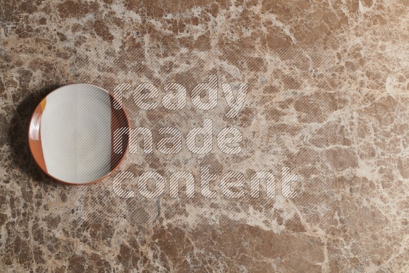A decorative pottery plate on beige marble background