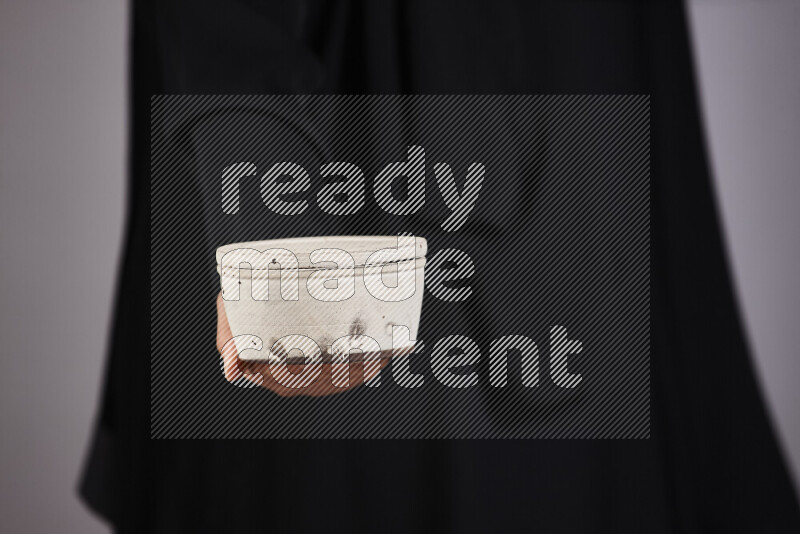 A woman in black abaya holding different pottery essentials in different positions