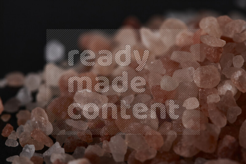 A bunch of coarse himalayan salt crystals on black background