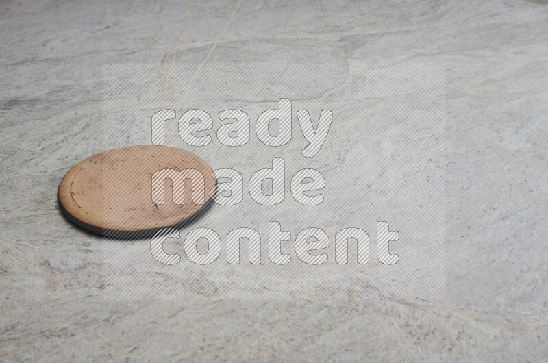 A flat pottery plate on grey marble background
