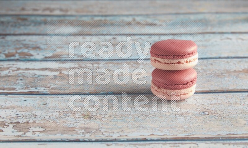 45º Shot of two Pink Litchi Raspberry macarons on light blue wooden background