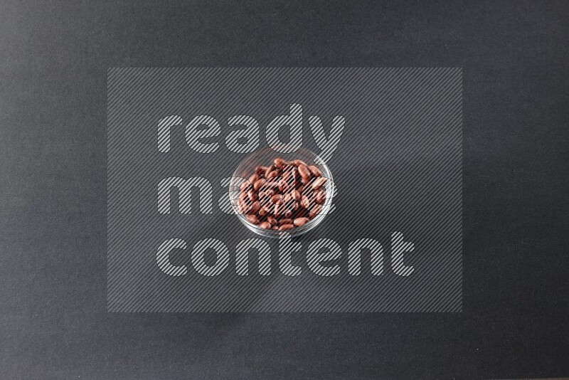A glass bowl full of red skin peanuts on a black background in different angles