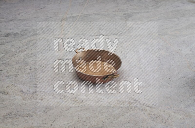 A small copper pan on grey marble background