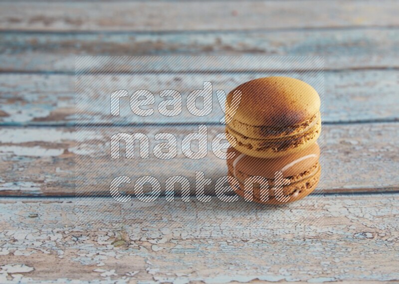 45º Shot of of two assorted Brown Irish Cream, and Yellow Crème Brulée macarons on light blue background