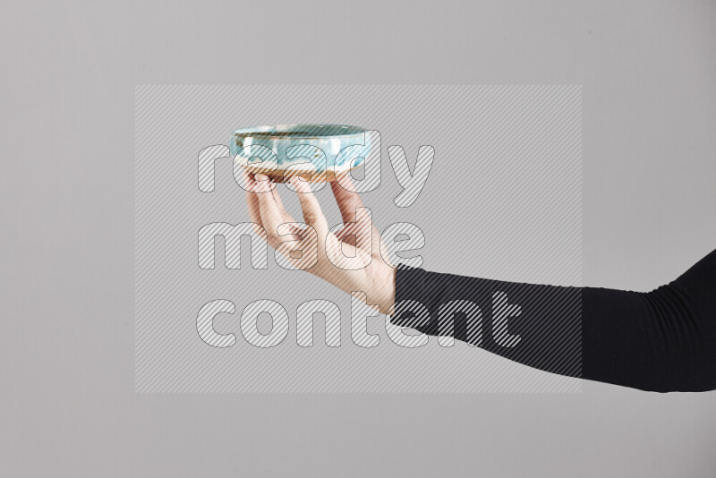 A woman in black abaya holding different pottery essentials in different positions