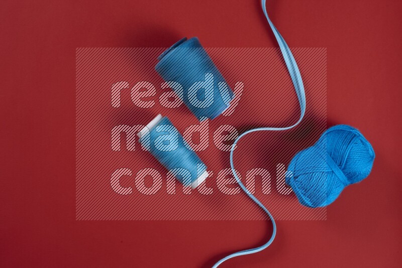 A blue and red collection of sewing and tailoring tools arranged on a red background