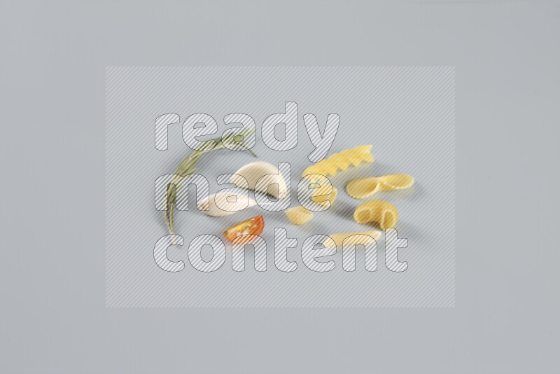 Raw pasta with different ingredients such as cherry tomatoes, garlic, onions, red chilis, black pepper, white pepper, bay laurel leaves, rosemary, cardamom and mushrooms on light blue background