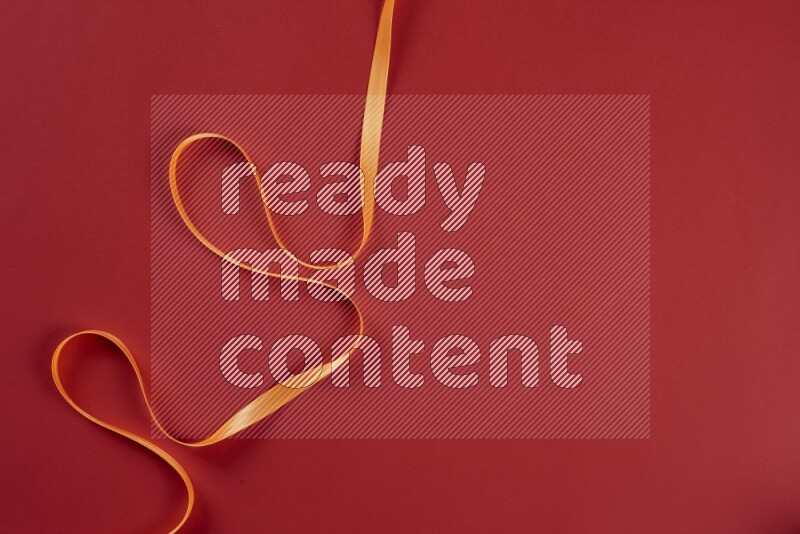 An orange collection of sewing and tailoring tools arranged on a red background