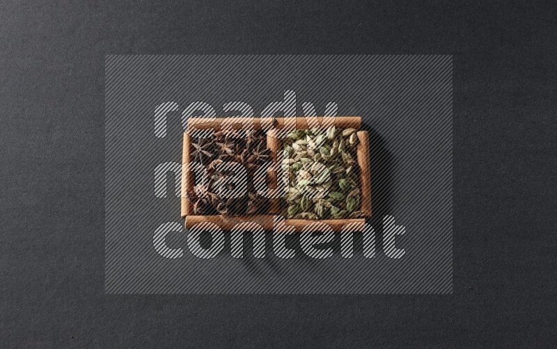 2 squares of cinnamon sticks full of cardamom and star anise on black flooring