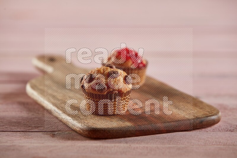 Vanilla mini cupcake topped with chocolate chips on a wooden board