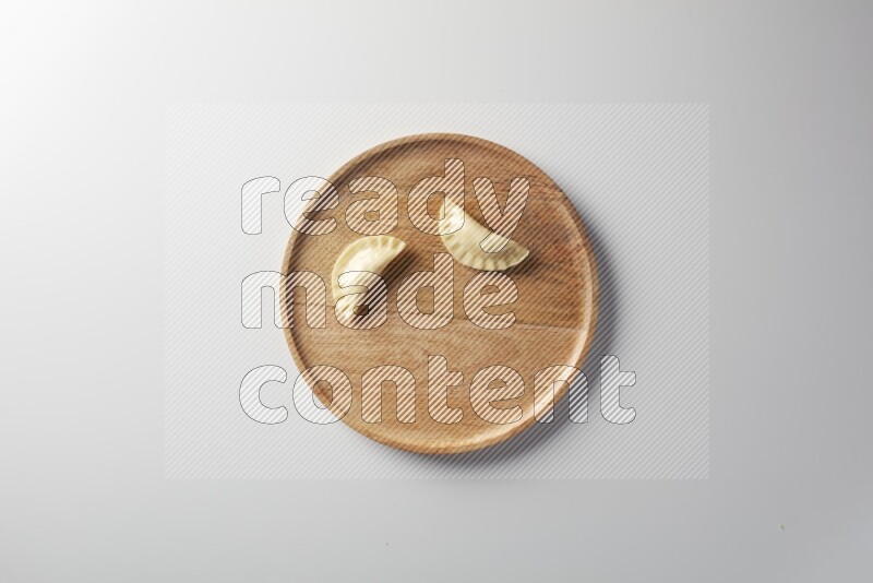 Two Sambosas on a wooden round plate on a white background