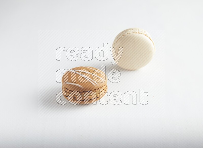 45º Shot of of two assorted Brown Irish Cream, and White Caramel fleur de sel macarons on white background