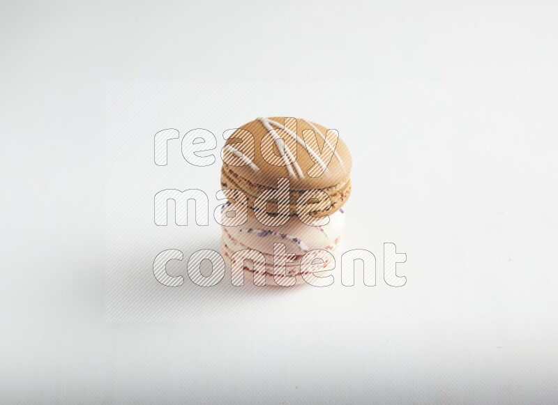 45º Shot of of two assorted Brown Irish Cream, and pink orange blossom macarons on white background
