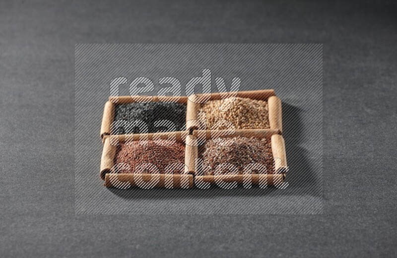 4 squares of cinnamon sticks full of flaxseeds, garden cress, black seeds and mustard seeds on black flooring