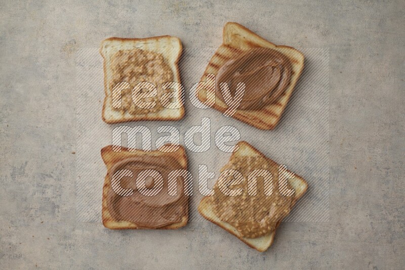 Creamy and crunchy peanut butter on a toasted white toast slices on a light blue textured background