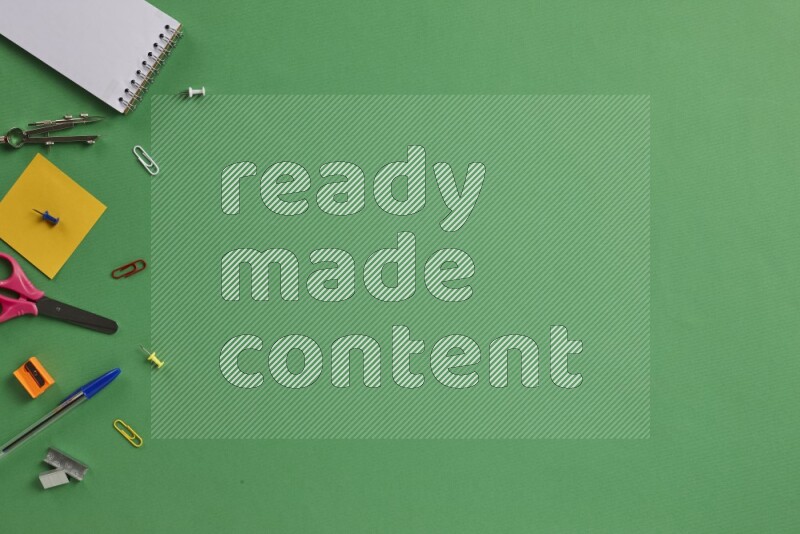 Different school supplies on green background
