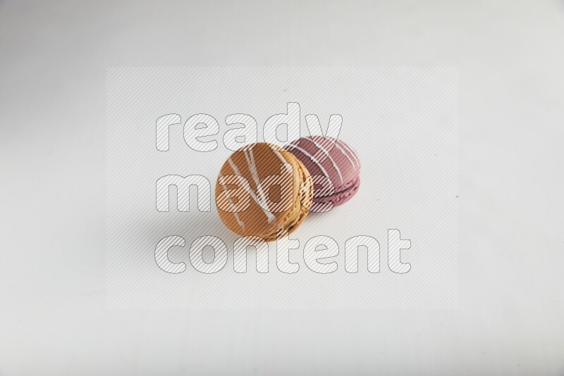 45º Shot of of two assorted Brown Irish Cream, and Red Poppy Flower macarons on white background