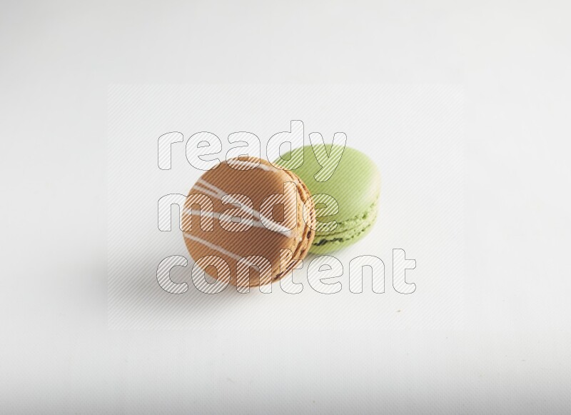 45º Shot of of two assorted Brown Irish Cream, and Green Pistachio macarons on white background