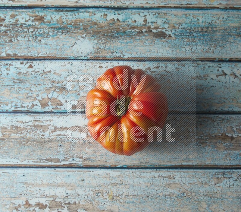 Single topview Heirloom tomato on a blue rustic wooden background