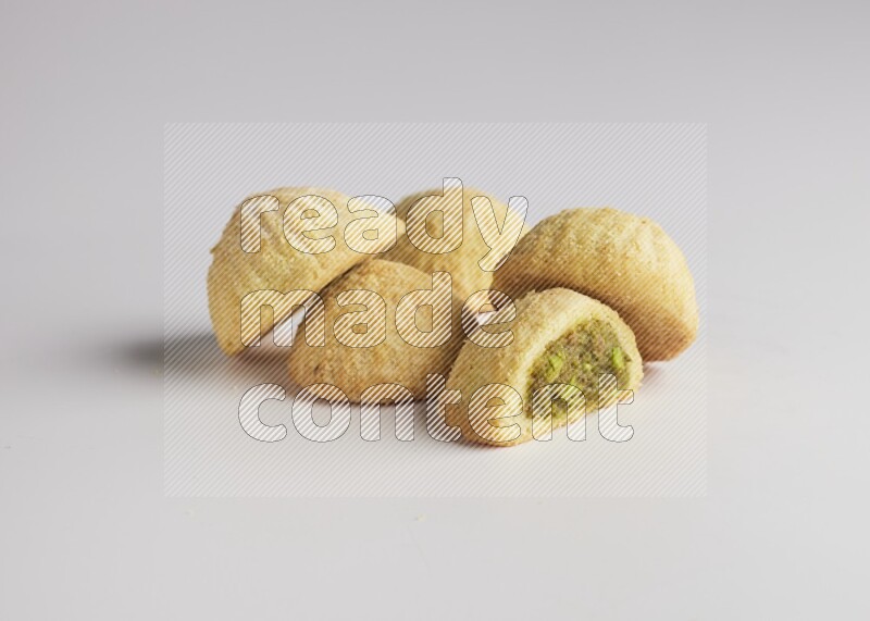 Five Pieces of Maamoul filled with pistachio  paste one of them is cut direct on white background