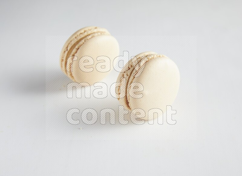 45º Shot of two White Caramel fleur de sel macarons on white background