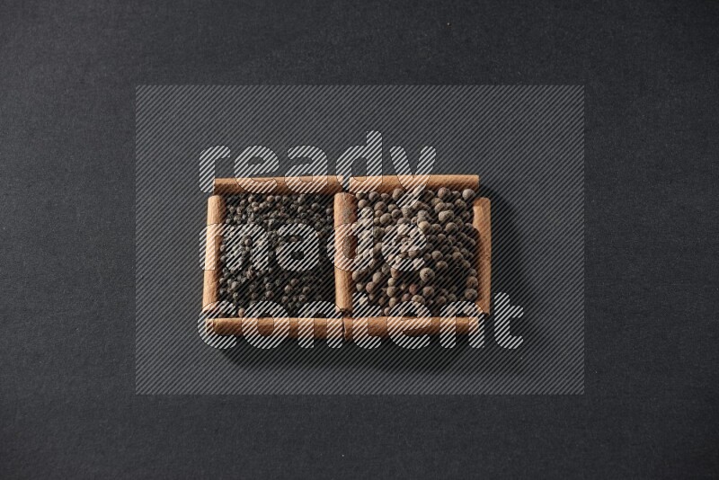 2 squares of cinnamon sticks full of black peppers and allspice on black flooring