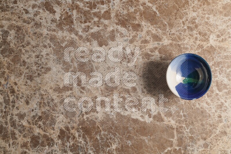 A multicolored pottery bowl on beige marble background