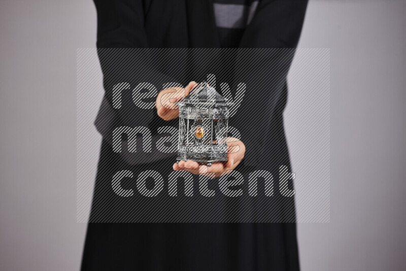 A woman in black abaya holding different ramadan lanterns in different positions