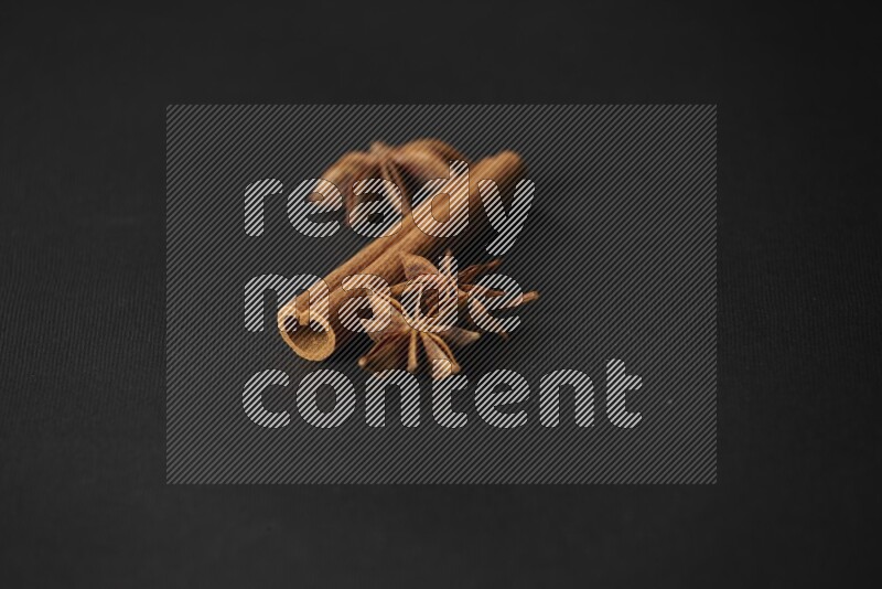 Star Anise herb and a cinnamon stick on a black background