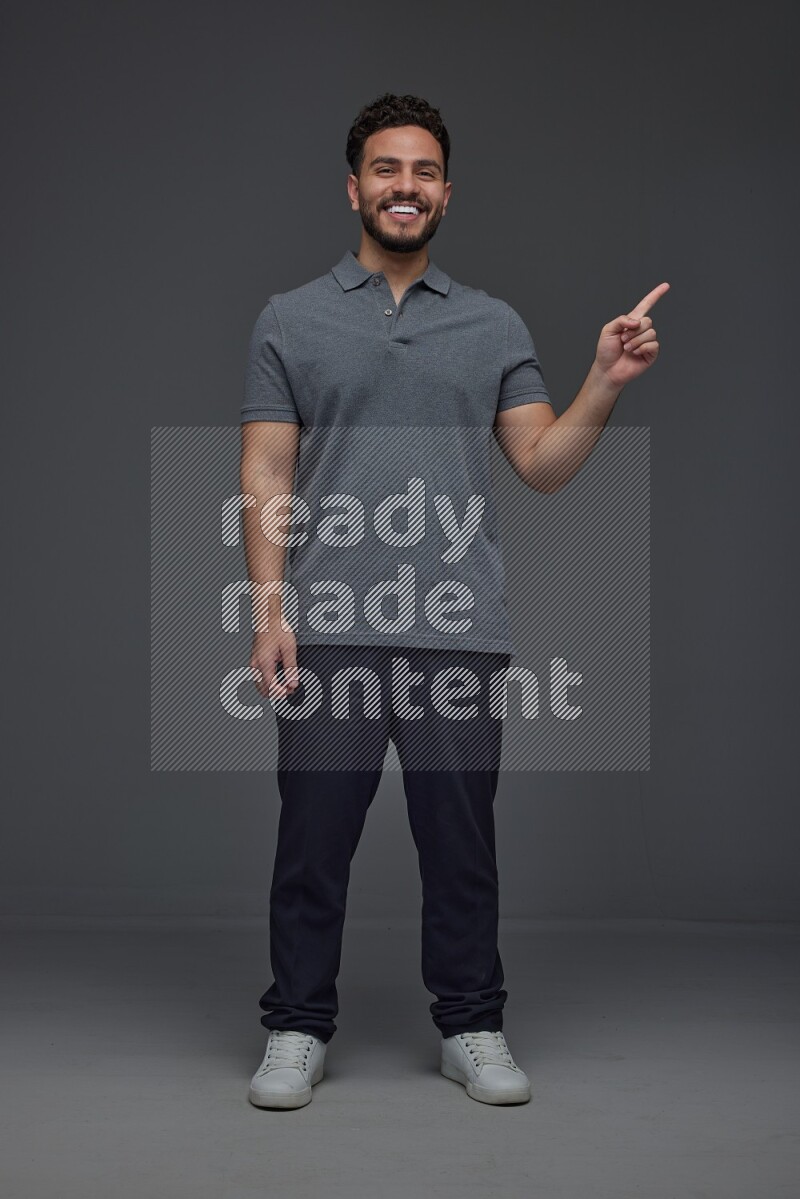 A man wearing casual standing and making multi hand gestures eye level on a gray background