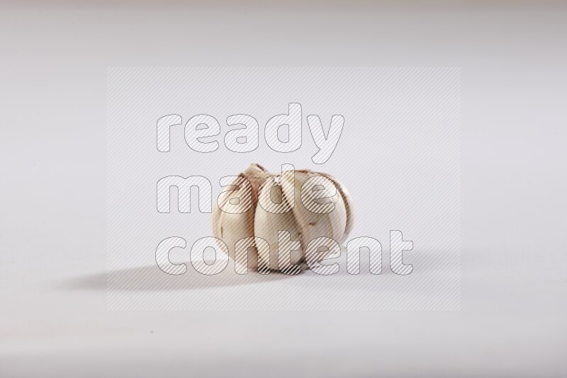 A whole garlic bulb placed on a white flooring