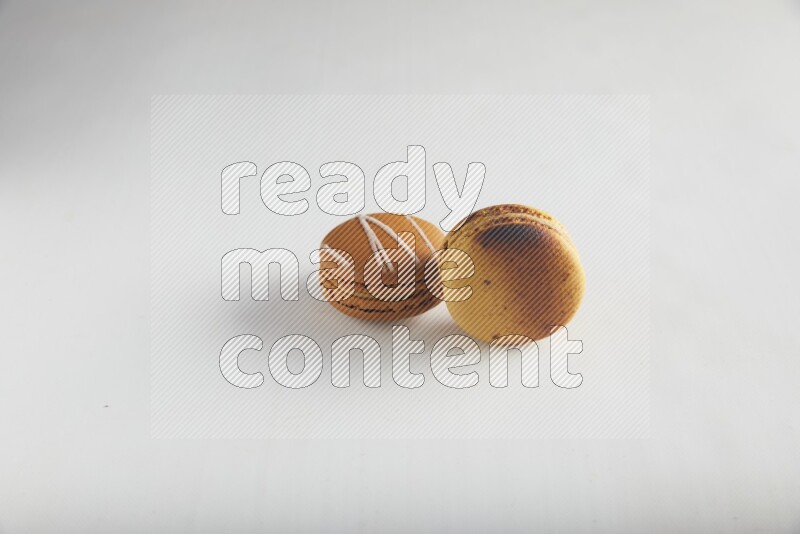 45º Shot of of two assorted Brown Irish Cream, and Yellow Crème Brulée macarons on white background