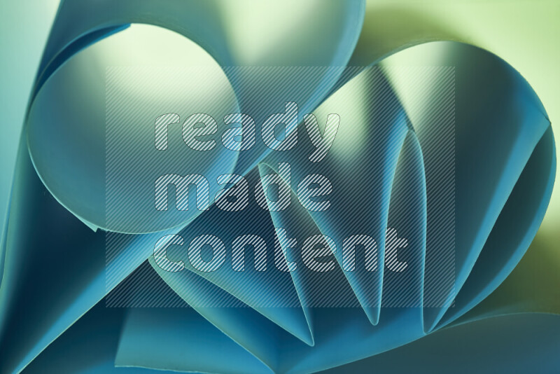 An artistic display of paper folds creating a harmonious blend of geometric shapes, highlighted by soft lighting in green and blue tones