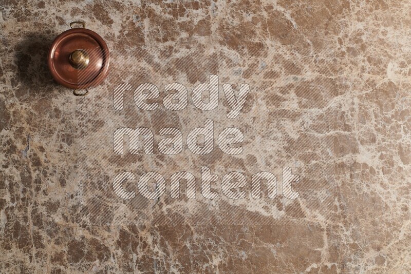A small copper pot on beige marble background