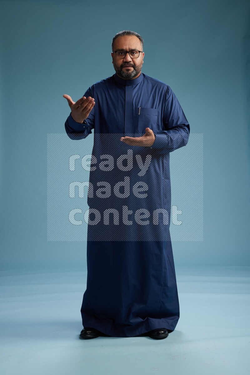 Saudi Man without shimag Standing Interacting with the camera on blue background