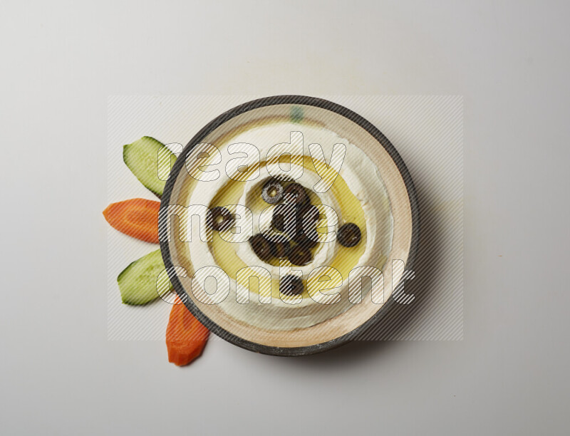 Lebnah garnished with sliced olives in a pottery plate on a white background