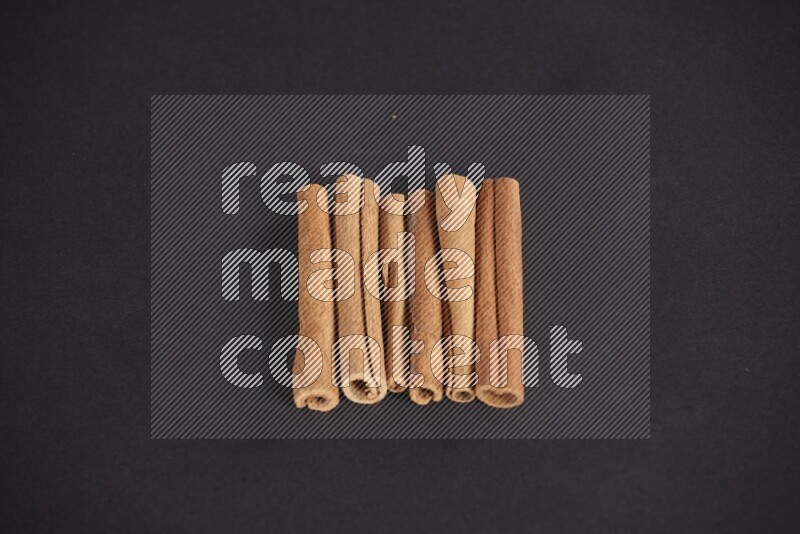 Cinnamon sticks stacked on black flooring