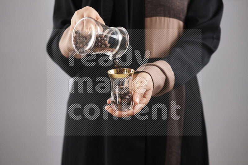 Woman in abaya holding different kinds of coffee beans in different positions