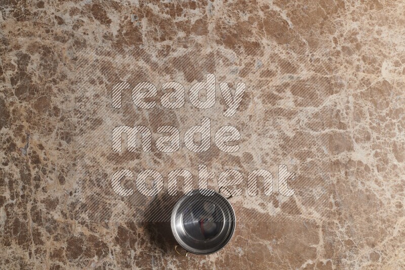 A small copper pot on beige marble background