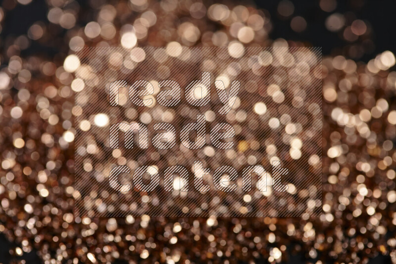 Bronze shimmering fragments of glass scattered on a black background