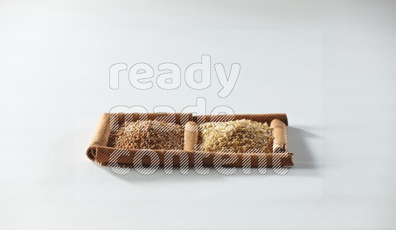 مربعان من أعواد القرفة ممتلئان بحبوب الخردل وبذور السمسم علي خلفية بيضاء