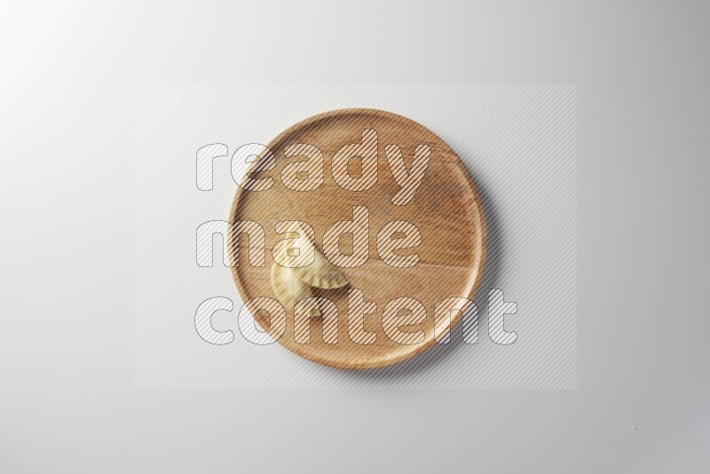Two Sambosas on a wooden round plate on a white background