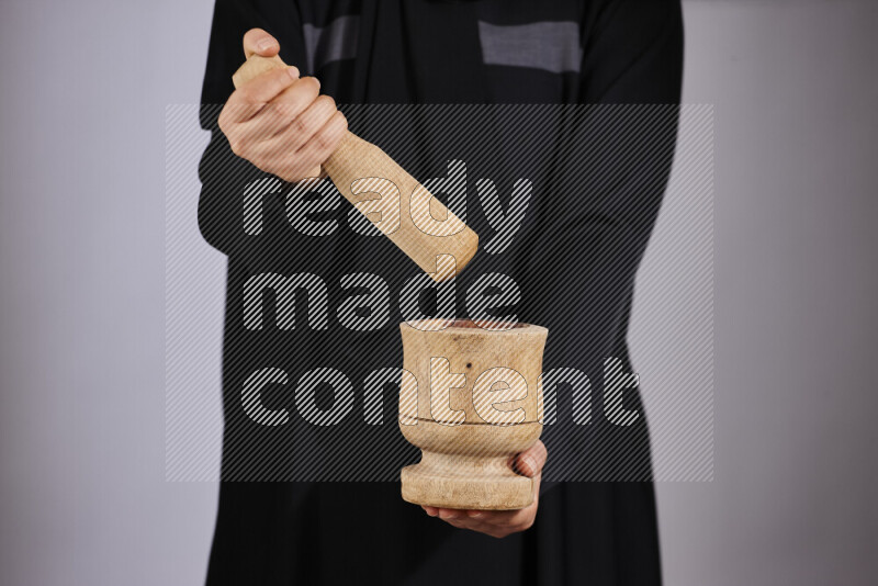 A woman in black abaya holding different wooden essentials in different positions
