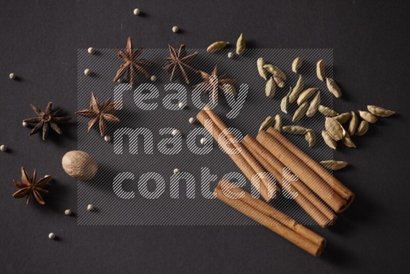 Cinnamon sticks, cardamom, star anise, nutmeg and white peppers on a black background