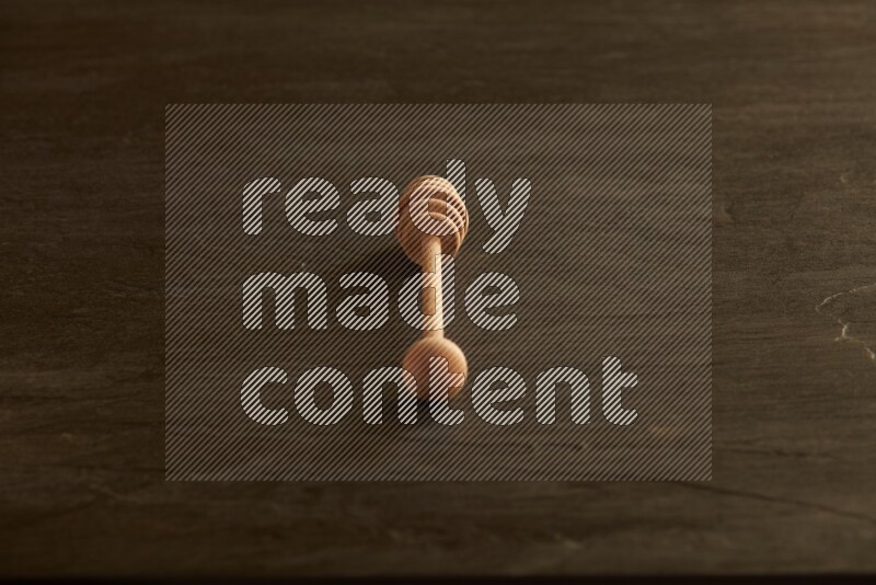 Wooden honey dipper on black slate background