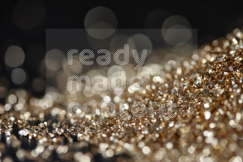 Gold shimmering fragments of glass scattered on a black background