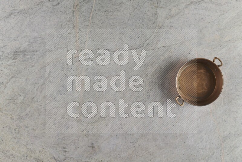 A small copper pan on grey marble background