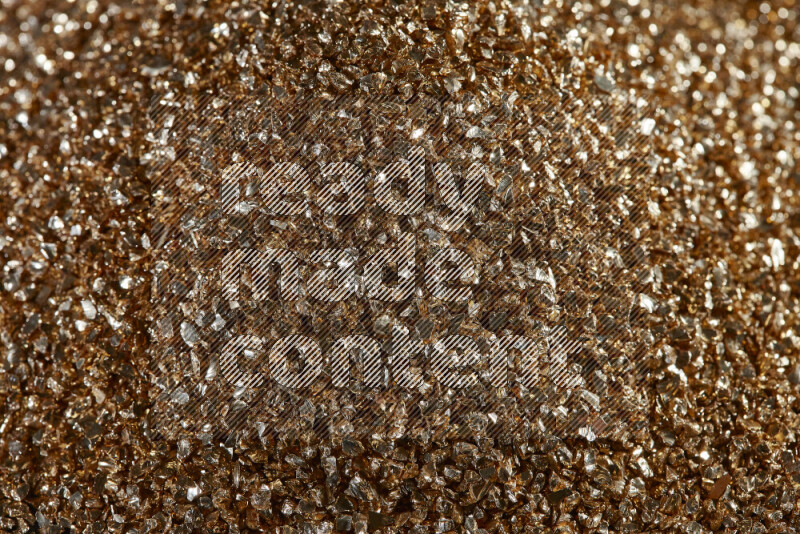 Gold shimmering fragments of glass scattered on a black background