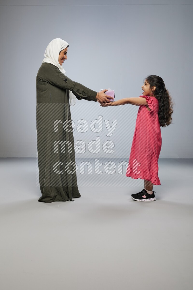 A girl giving a gift to her mother on gray background